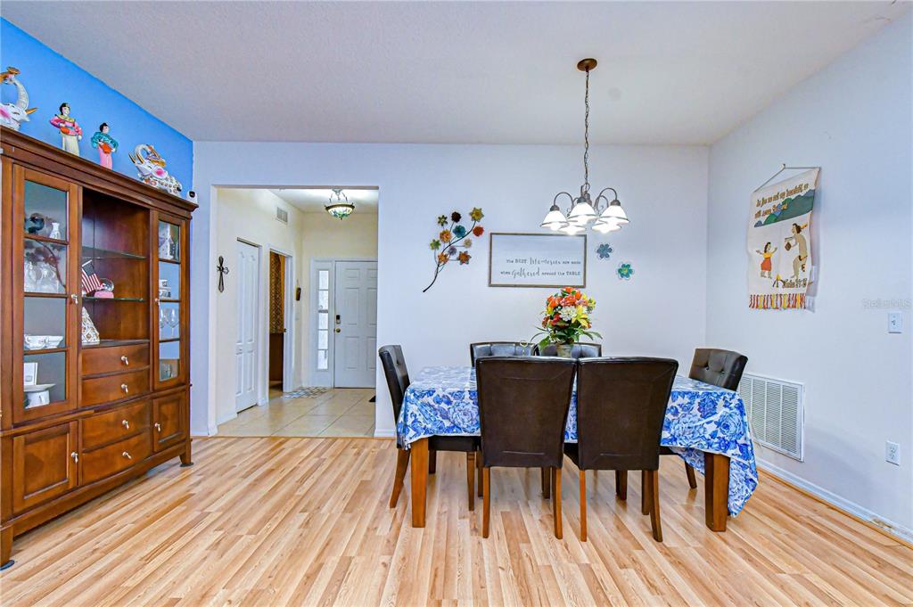 A dining room features a wooden hutch, a table with blue floral cloth, and light flooring — 6252 TWIN BRIDGES DRIVE, ZEPHYRHILLS, FL