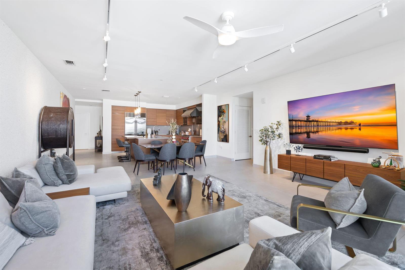 A modern open-concept living room and kitchen featuring a large television and dining area — 3581 E Glencoe Street # 408, Miami FL 33133, MIAMI, FL