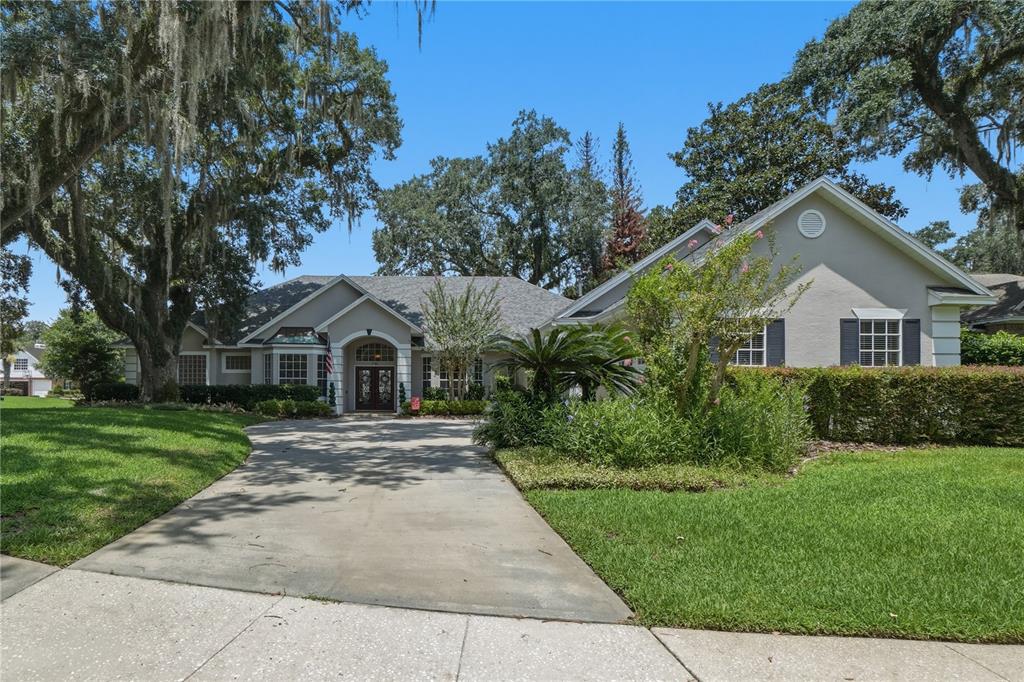 A single-story house with a concrete driveway, a front entrance, and mature trees — 3780 CHARLESTON LOOP, OVIEDO, FL