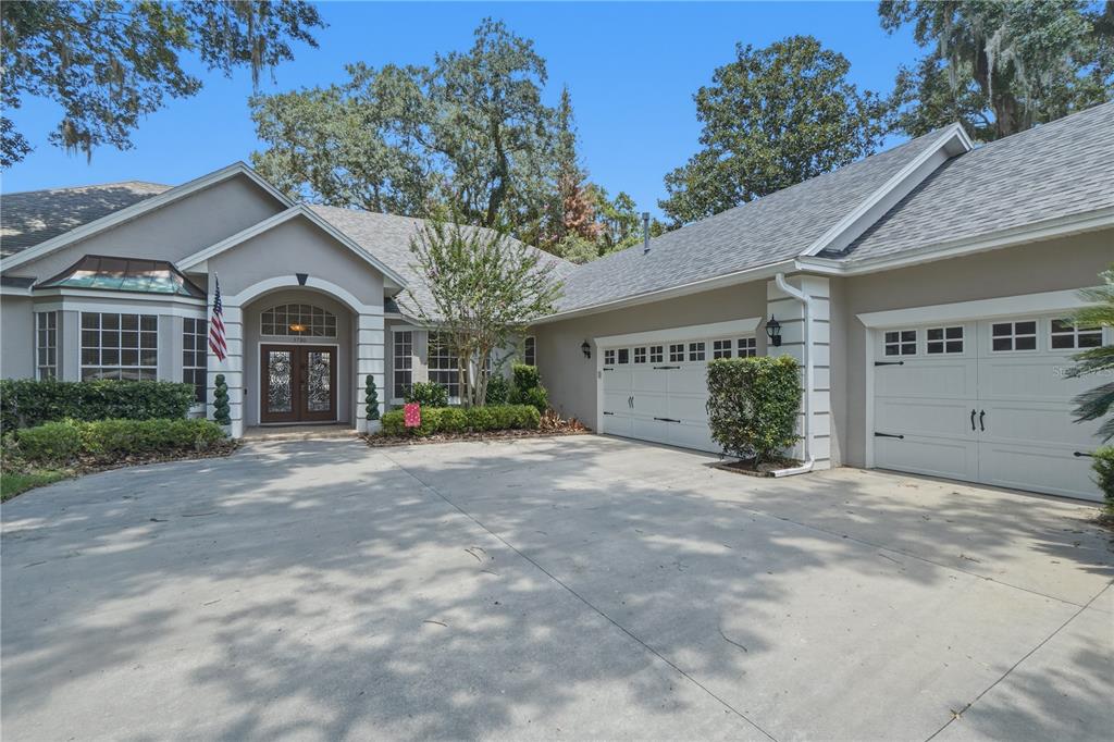 A single-story house with a concrete driveway, a three-car garage, and a covered entryway — 3780 CHARLESTON LOOP, OVIEDO, FL