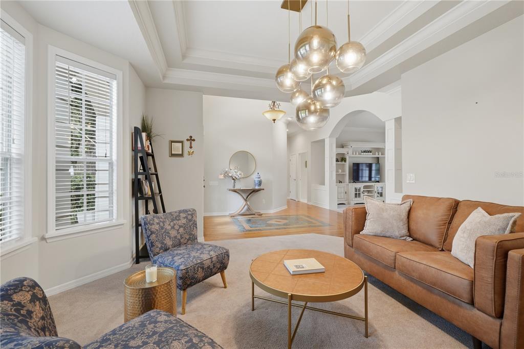 A living room features a leather sofa, two patterned armchairs, and a modern globe chandelier — 3780 CHARLESTON LOOP, OVIEDO, FL