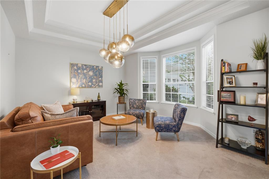 A living room features a leather sofa, two patterned armchairs, and a modern globe chandelier — 3780 CHARLESTON LOOP, OVIEDO, FL