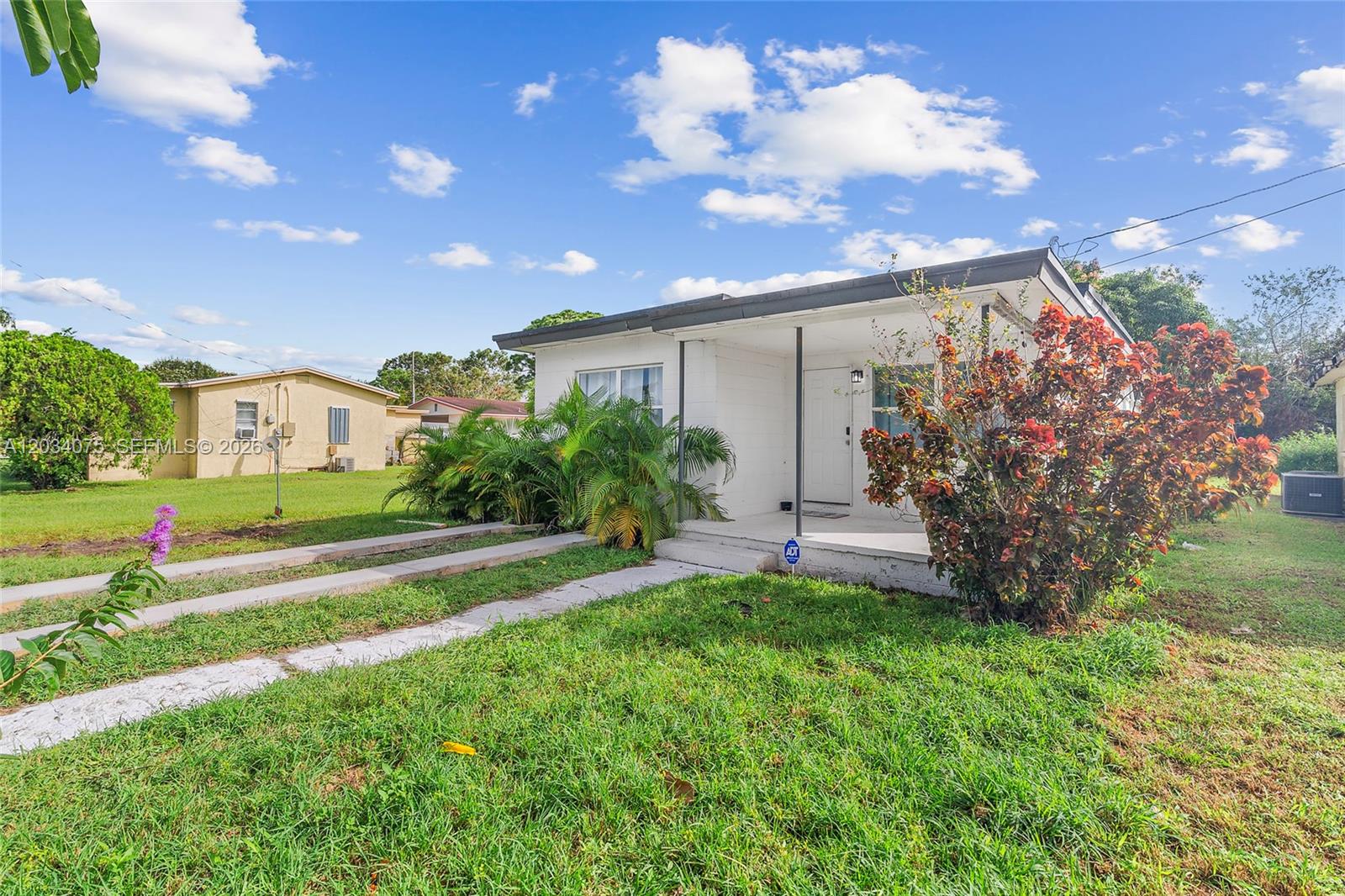 A white single-story house with a covered front porch and a grassy front yard — 1408 N 23rd St, Fort Pierce FL 34950, FORT PIERCE, FL