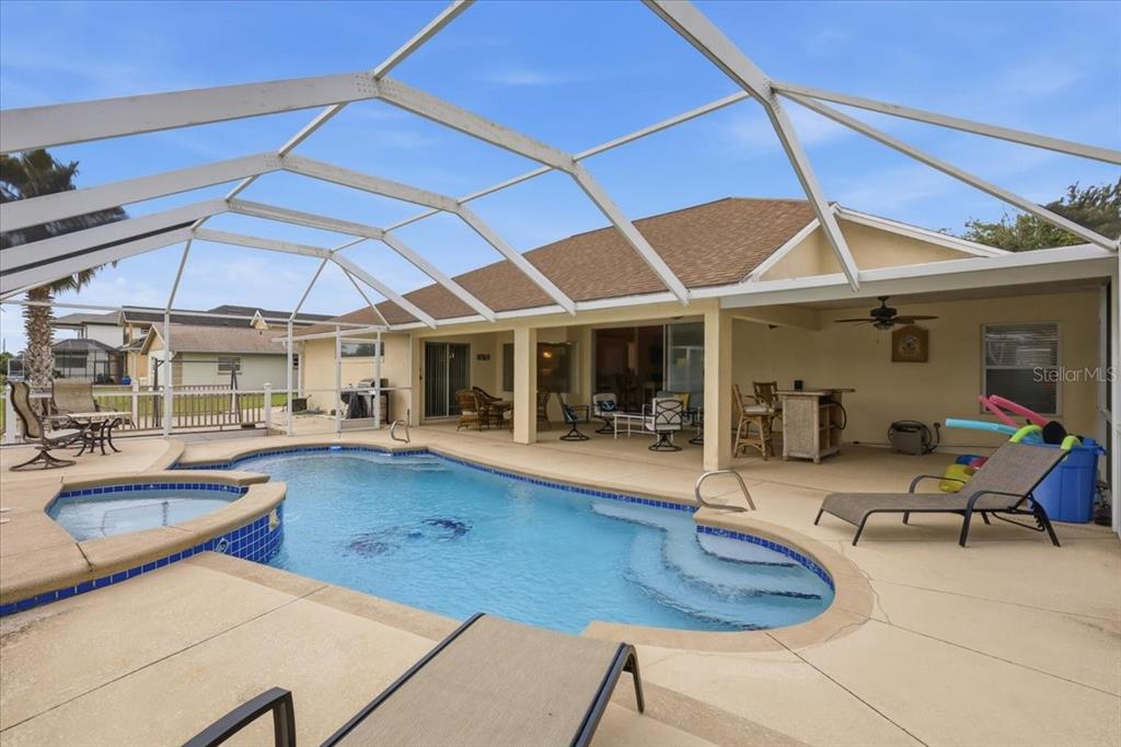 A screened-in patio features a swimming pool, a hot tub, and outdoor seating — 36 CLOVERDALE COURT N, PALM COAST, FL