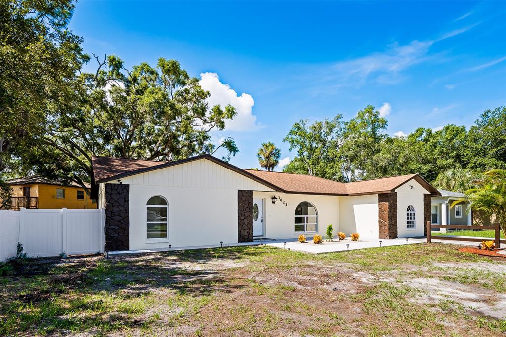 A single-story house with white stucco walls, dark stone accents, and a brown shingled roof — 3823 E NORFOLK STREET, TAMPA, FL