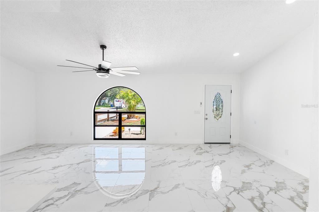 A bright room with white walls, a ceiling fan, arched window, and polished marble-look flooring — 3823 E NORFOLK STREET, TAMPA, FL