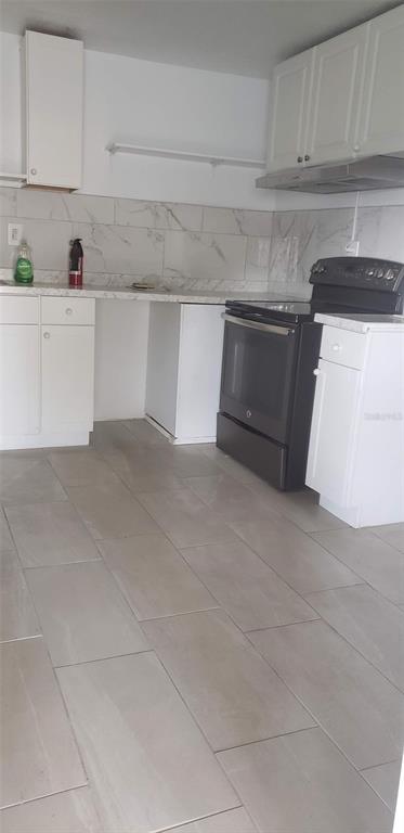 A kitchen with white cabinets, a black stove, and light-colored tile flooring — 1118 HARRIS LANE, CLEARWATER, FL