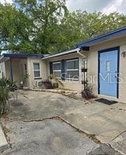 The exterior of a single-story house features a light blue front door and concrete driveway — 1118 HARRIS LANE, CLEARWATER, FL