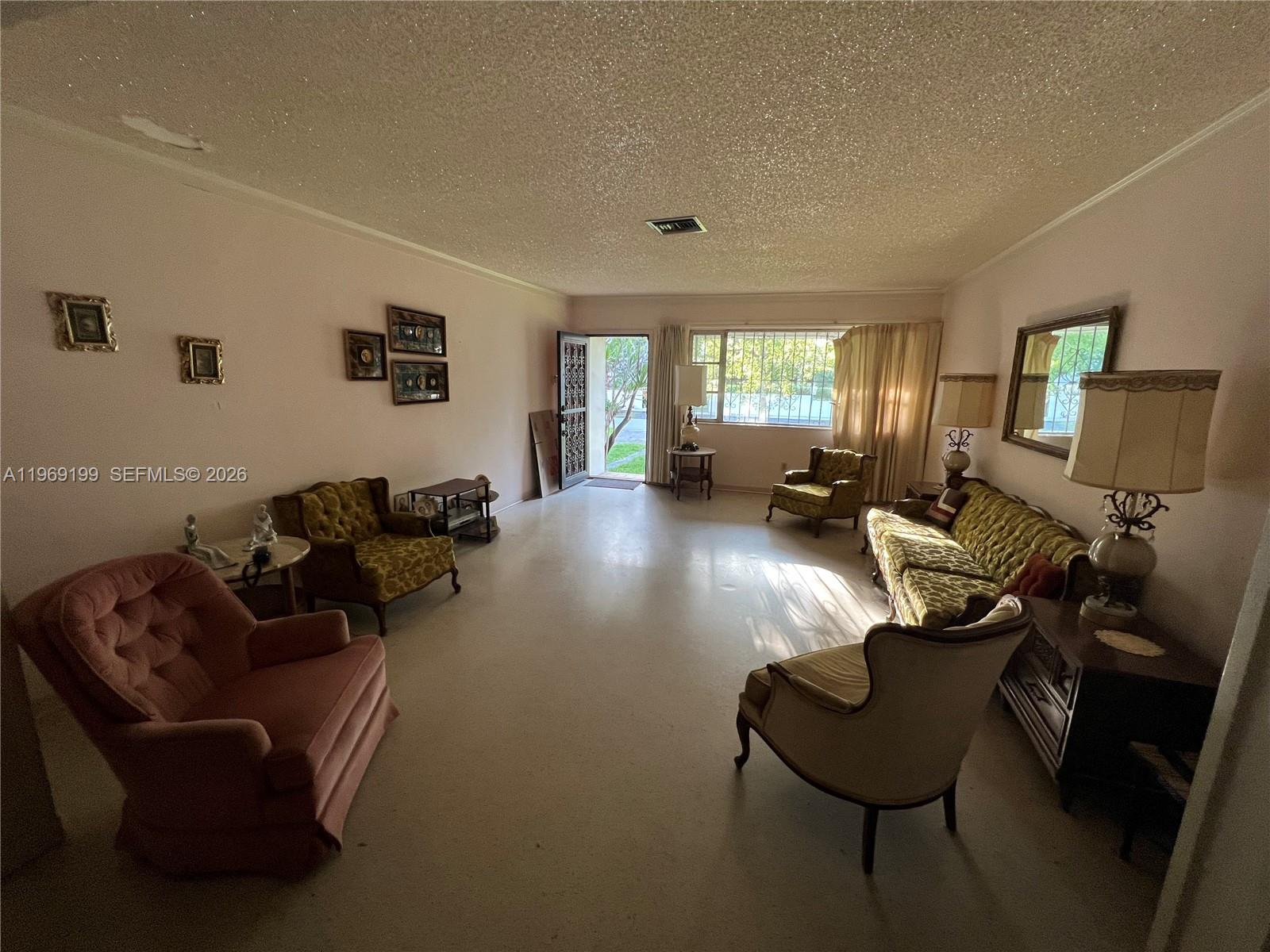 A living room features vintage furniture, a textured ceiling, and an open doorway to outside — 812 Columbus Blvd, Coral Gables FL 33134, CORAL GABLES, FL