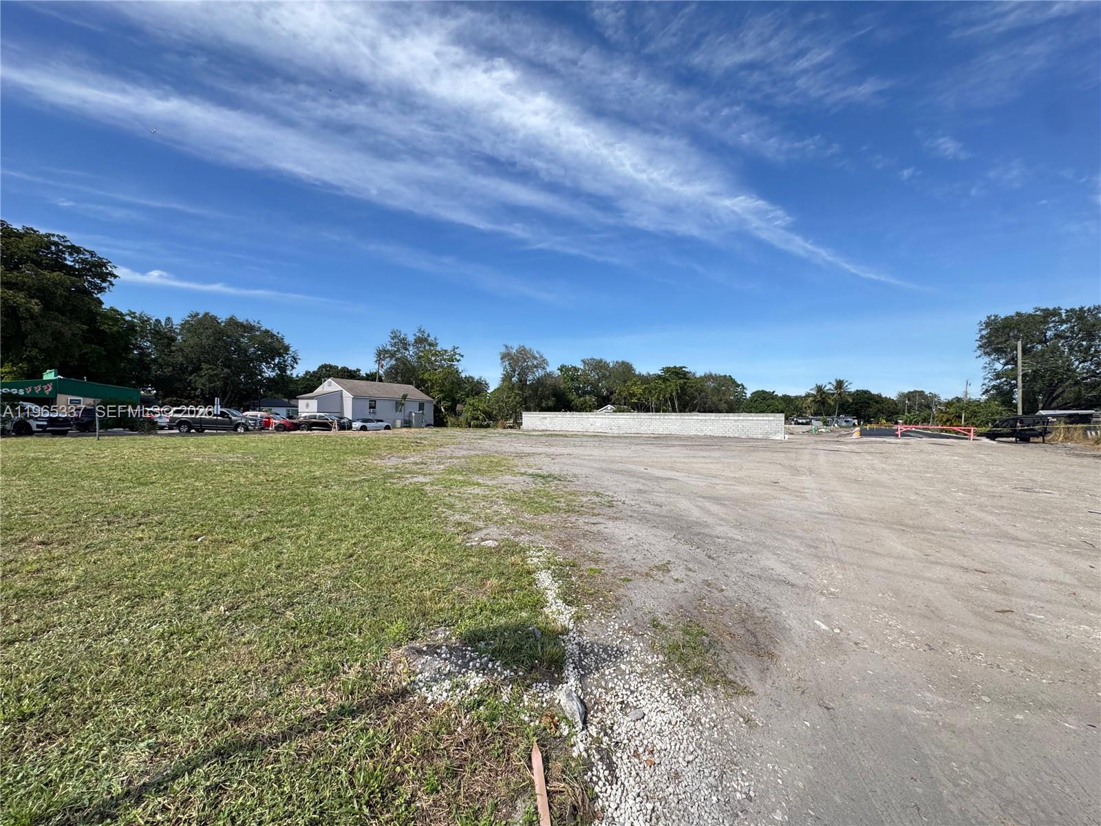 A large, flat, vacant lot features a mix of grass and dirt with a perimeter wall — 2621 Griffin Rd, Dania Beach FL 33312, DANIA BEACH, FL
