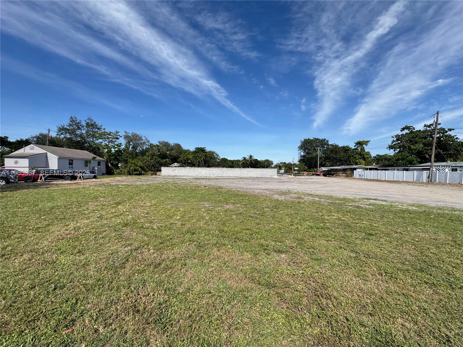 A large, flat, grassy vacant lot features a concrete block wall in the background — 2621 Griffin Rd, Dania Beach FL 33312, DANIA BEACH, FL