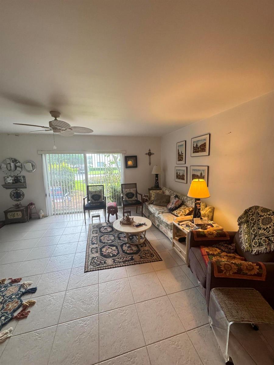 A living room with tile flooring, a ceiling fan, sliding glass doors, and patterned furniture — 90 South Boulevard # 1c, Boynton Beach FL 33435, BOYNTON BEACH, FL