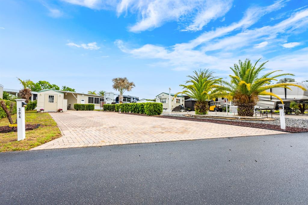A paved driveway leads to a small shed and mobile home with palm trees — 2410 LIMEWOOD AVENUE UNIT 304, CLERMONT, FL