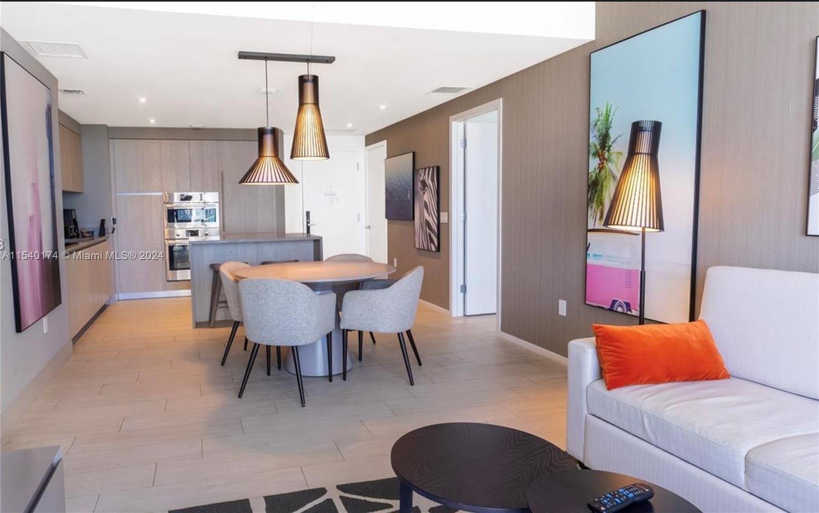 An open-concept living and dining area features light wood flooring, modern furniture, and pendant lighting — 4010 S Ocean Dr # R703, Hollywood FL 33019, HOLLYWOOD, FL