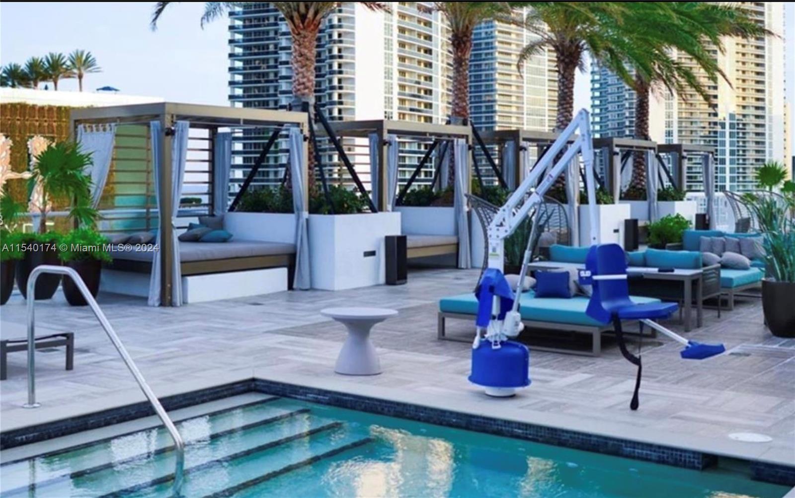 A swimming pool deck features cabanas, lounge seating, and a blue pool lift — 4010 S Ocean Dr # R703, Hollywood FL 33019, HOLLYWOOD, FL
