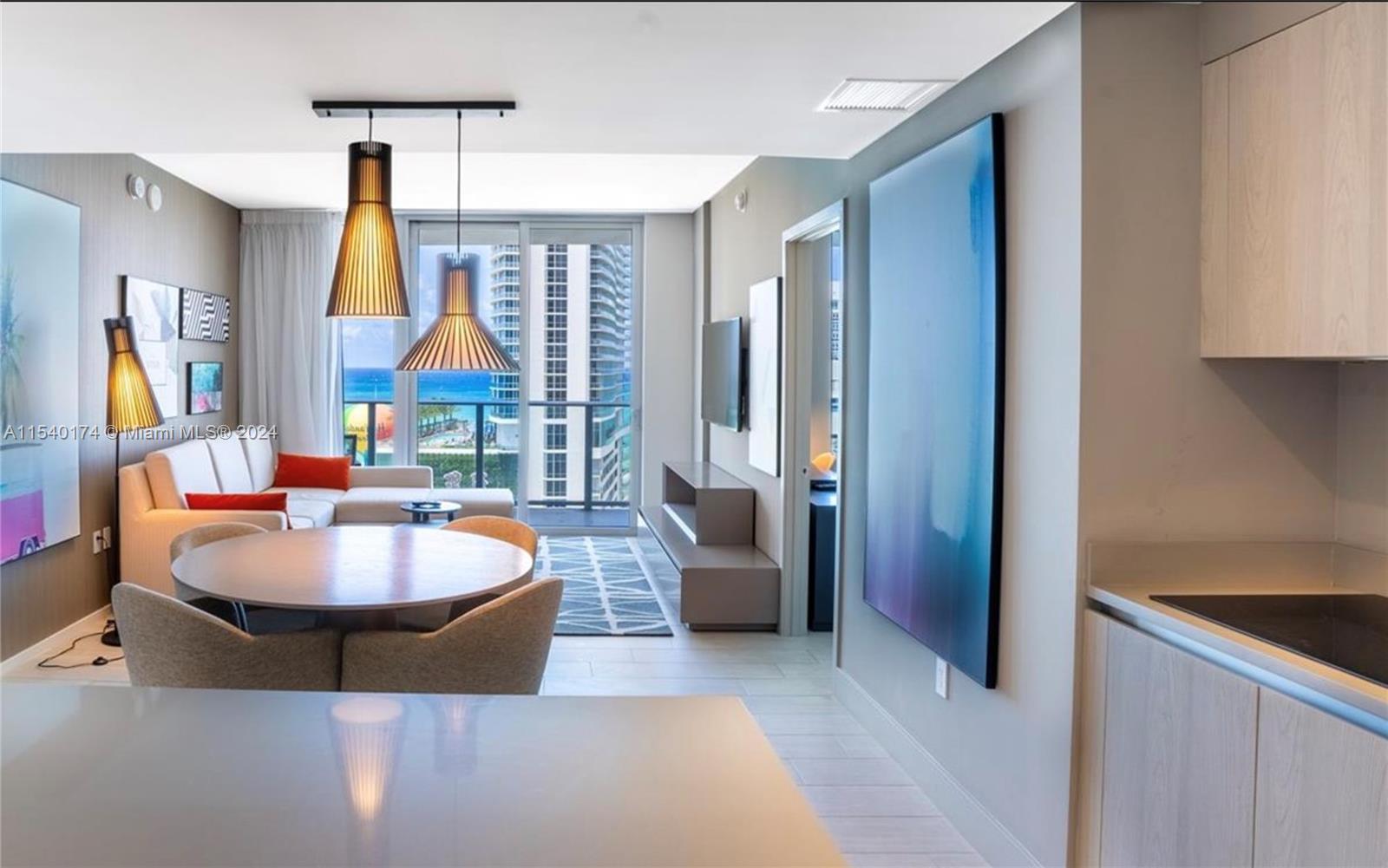 A modern living and dining area features a round table, sofa, and ocean view balcony — 4010 S Ocean Dr # R703, Hollywood FL 33019, HOLLYWOOD, FL