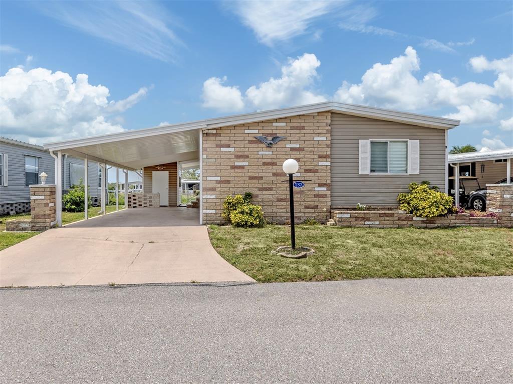 A single-story house with a brick facade, a carport, and a front lawn — 132 MARTINIQUE ROAD, NORTH PORT, FL