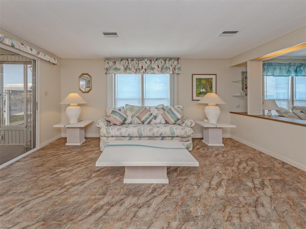 A living room features a floral sofa, matching end tables with lamps, and marble-patterned flooring — 132 MARTINIQUE ROAD, NORTH PORT, FL
