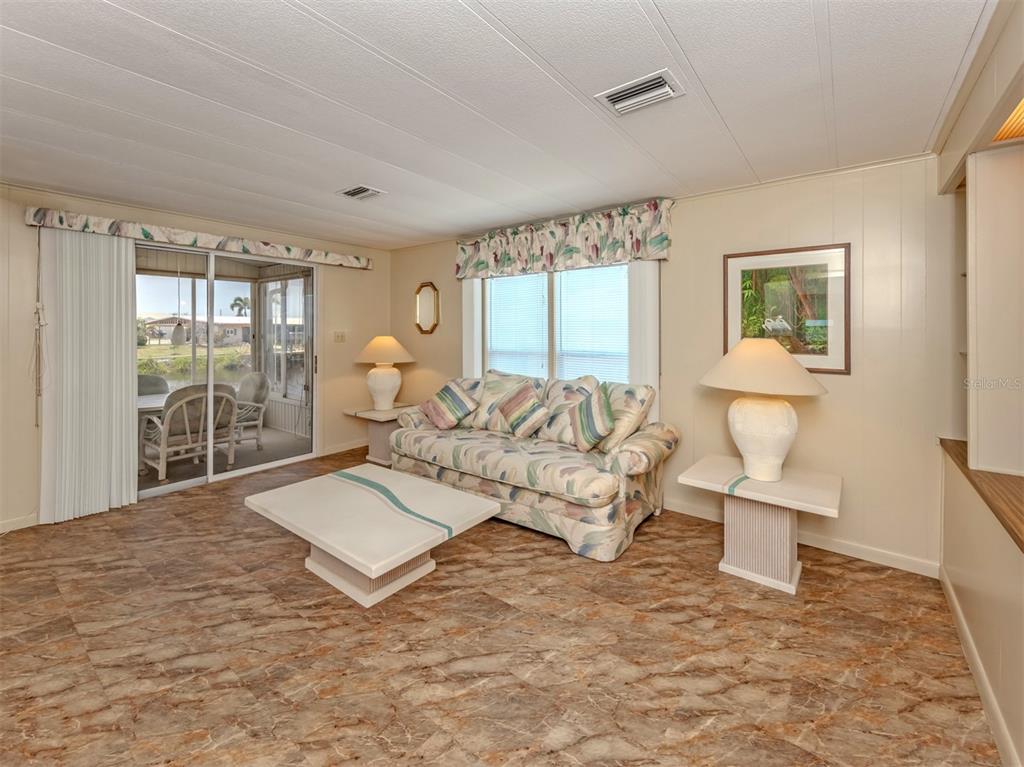 A living room features marble-patterned tile flooring, a patterned sofa, and a sliding glass door — 132 MARTINIQUE ROAD, NORTH PORT, FL