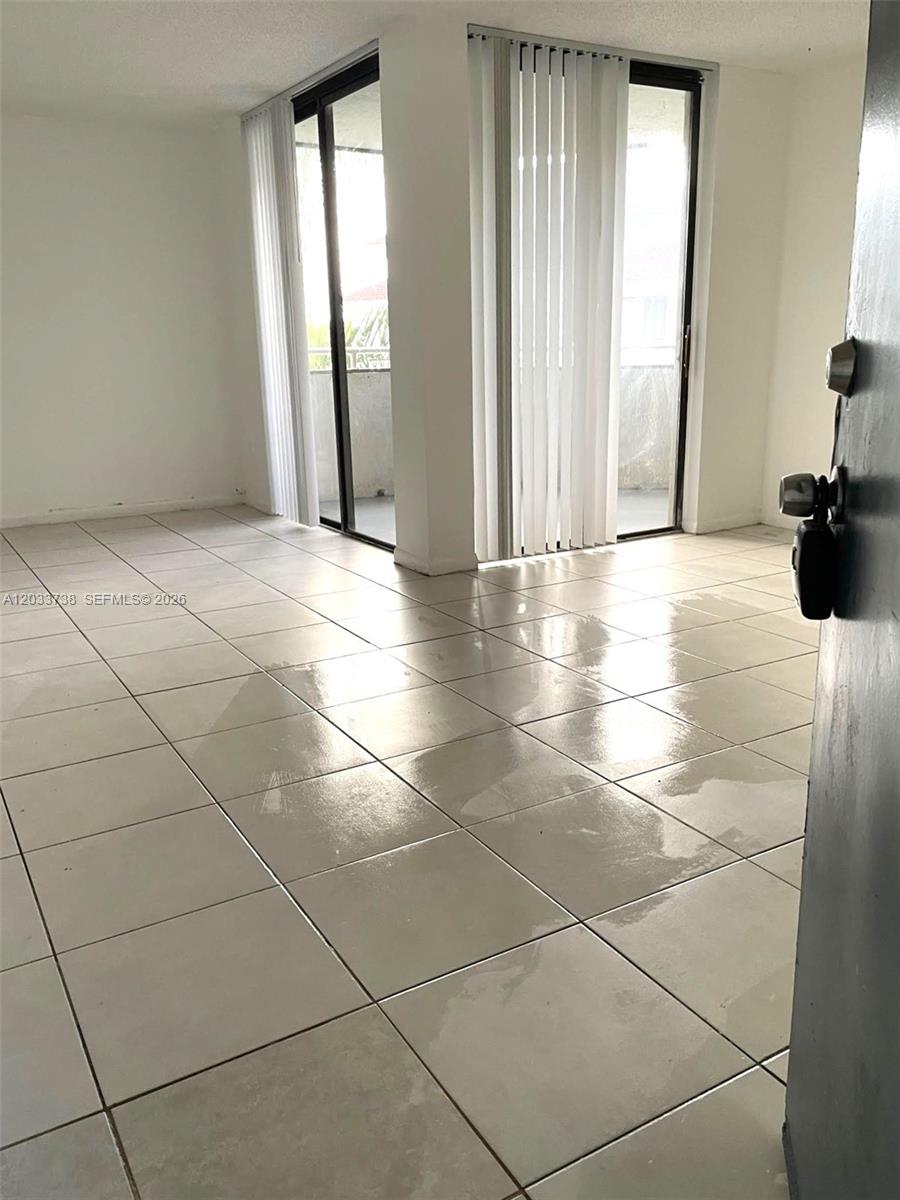 An empty room features large light-colored floor tiles and two sets of glass sliding doors — 8255 SW 152nd Ave # 405, Miami FL 33193, MIAMI, FL