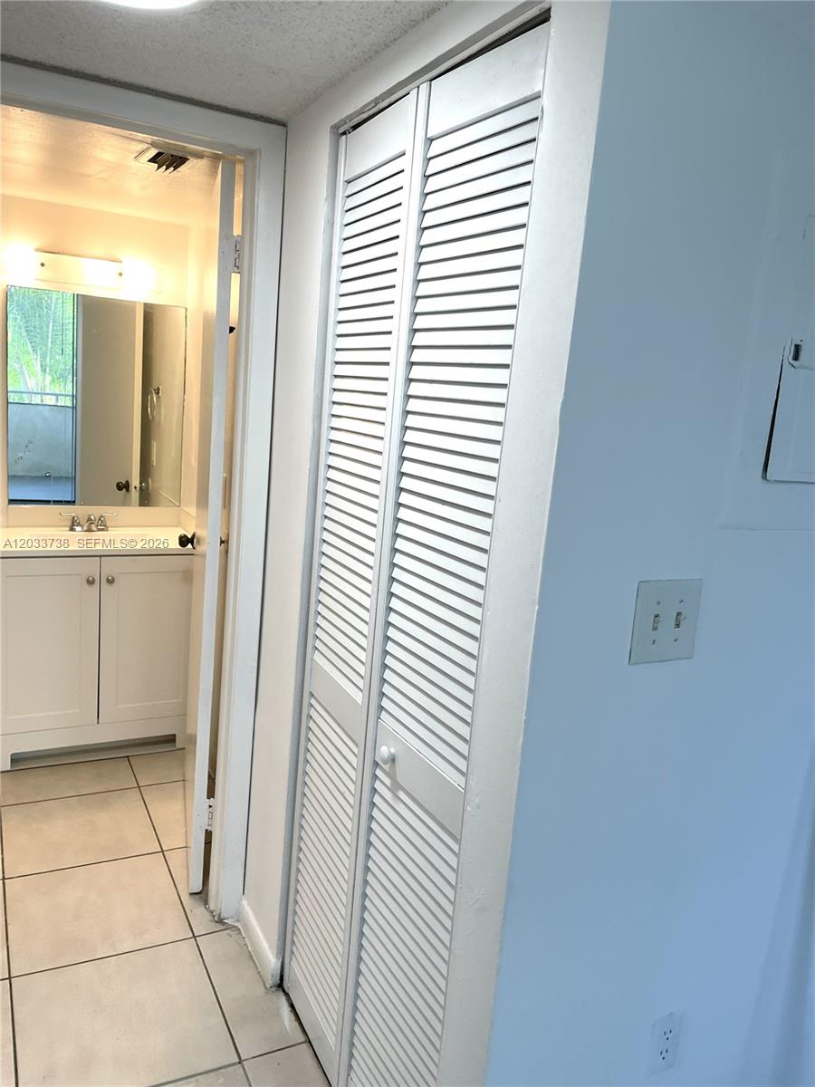 A hallway features a white louvered closet door next to a doorway leading to a bathroom — 8255 SW 152nd Ave # 405, Miami FL 33193, MIAMI, FL