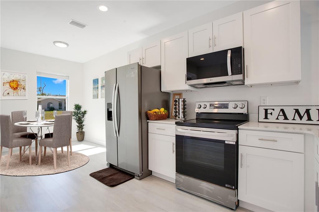 A kitchen features white cabinets, stainless steel appliances, and an adjacent dining area with chairs — 9416 ANITA AVENUE, ENGLEWOOD, FL