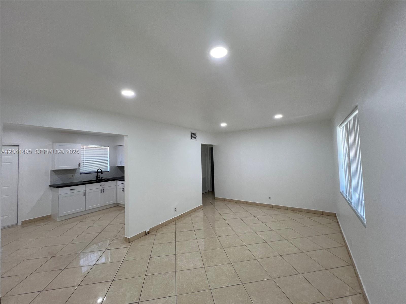 An open-concept living area features beige tile flooring, recessed lighting, and an adjacent kitchen — MIAMI, FL