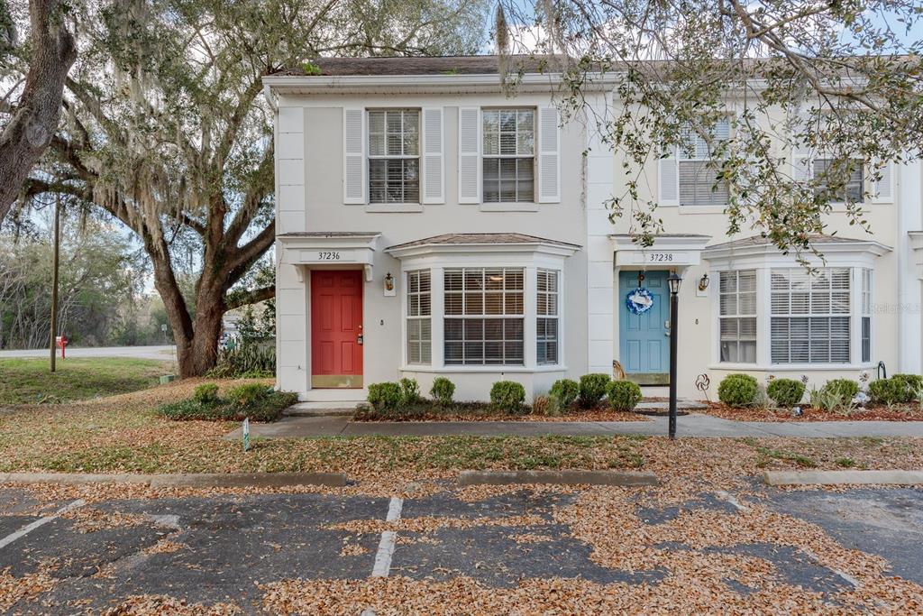 A two-story townhouse exterior features a red door, a blue door, and bay windows — 37236 EMBASSY PARK LANE UNIT 1, DADE CITY, FL
