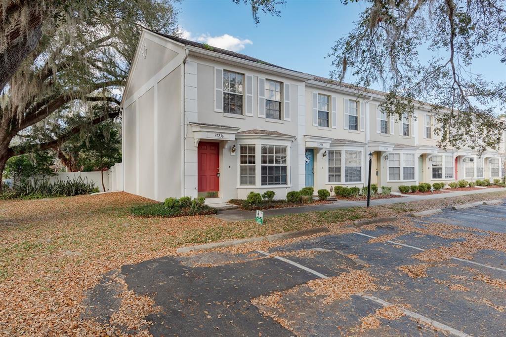A row of two-story townhomes with light-colored siding and a parking lot in front — 37236 EMBASSY PARK LANE UNIT 1, DADE CITY, FL