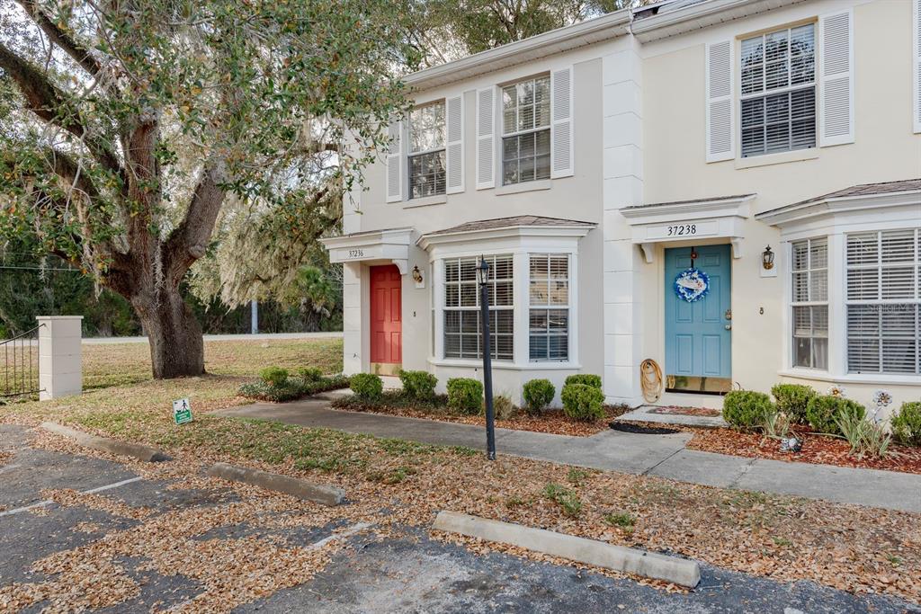 A two-story townhouse exterior features a red door, a blue door, and a bay window — 37236 EMBASSY PARK LANE UNIT 1, DADE CITY, FL