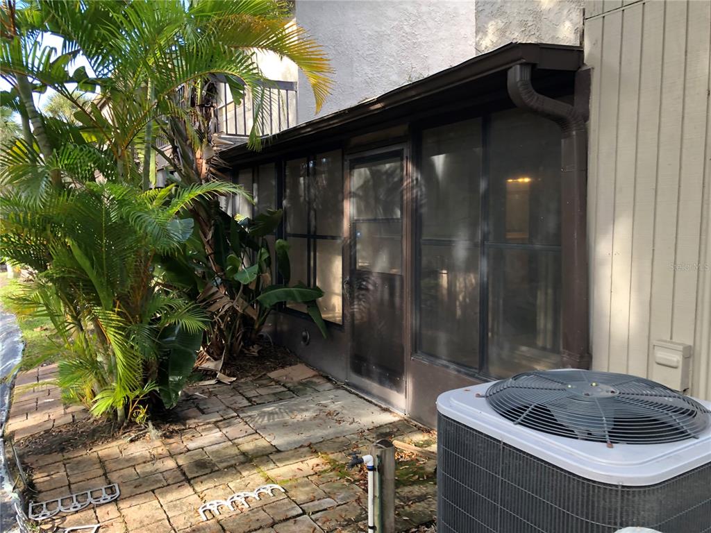 A screened-in patio area features a paved floor, a door, and an adjacent air conditioning unit — 6344 NEWTOWN CIRCLE UNIT 44A1, TAMPA, FL