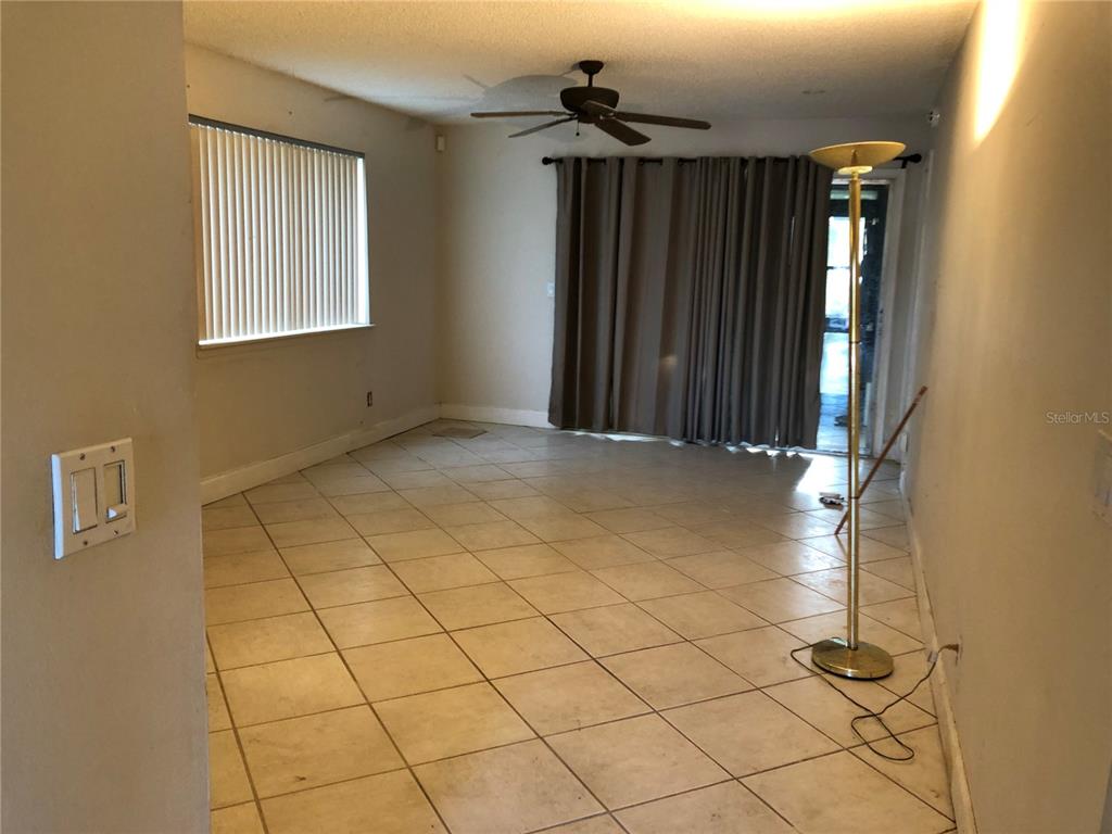 An empty room with beige tile flooring, a ceiling fan, and sliding glass doors — 6344 NEWTOWN CIRCLE UNIT 44A1, TAMPA, FL