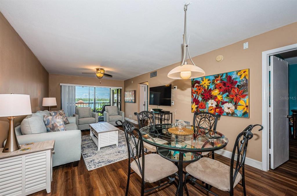 A living and dining area features wood-look flooring, a glass-top table, and a balcony view — 6295 BAHIA DEL MAR CIRCLE UNIT 204, ST PETERSBURG, FL