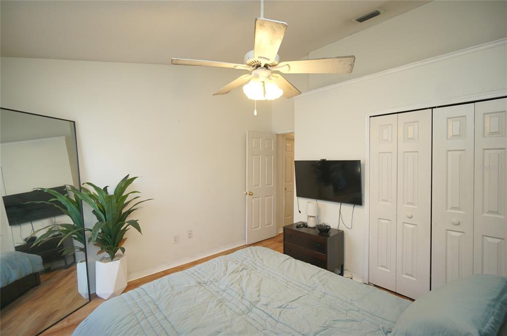 A bedroom features a ceiling fan, a wall-mounted television, a large mirror, and white closets — 6921 JAMESTOWN MANOR DRIVE, RIVERVIEW, FL