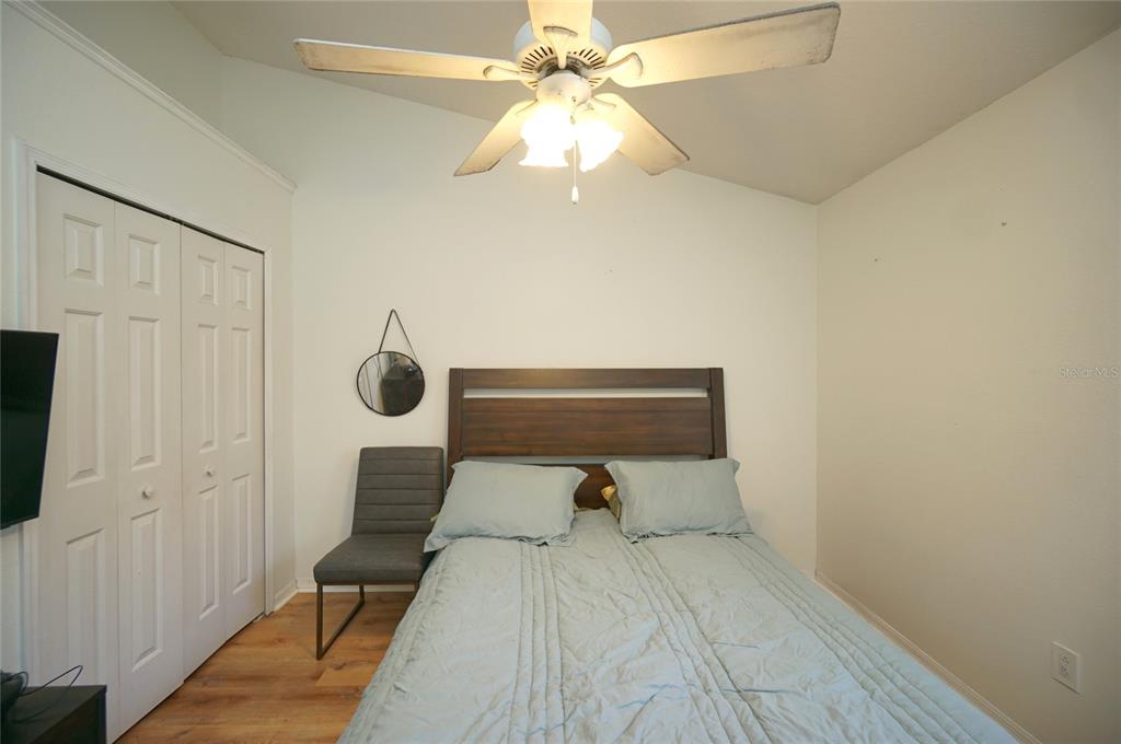 A bedroom features a bed with a wooden headboard, a ceiling fan, and a chair — 6921 JAMESTOWN MANOR DRIVE, RIVERVIEW, FL