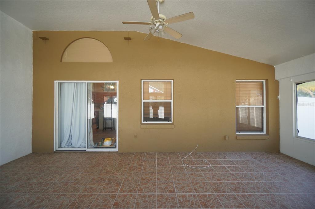 A covered patio with tiled flooring, a ceiling fan, and a tan wall with windows — 6921 JAMESTOWN MANOR DRIVE, RIVERVIEW, FL
