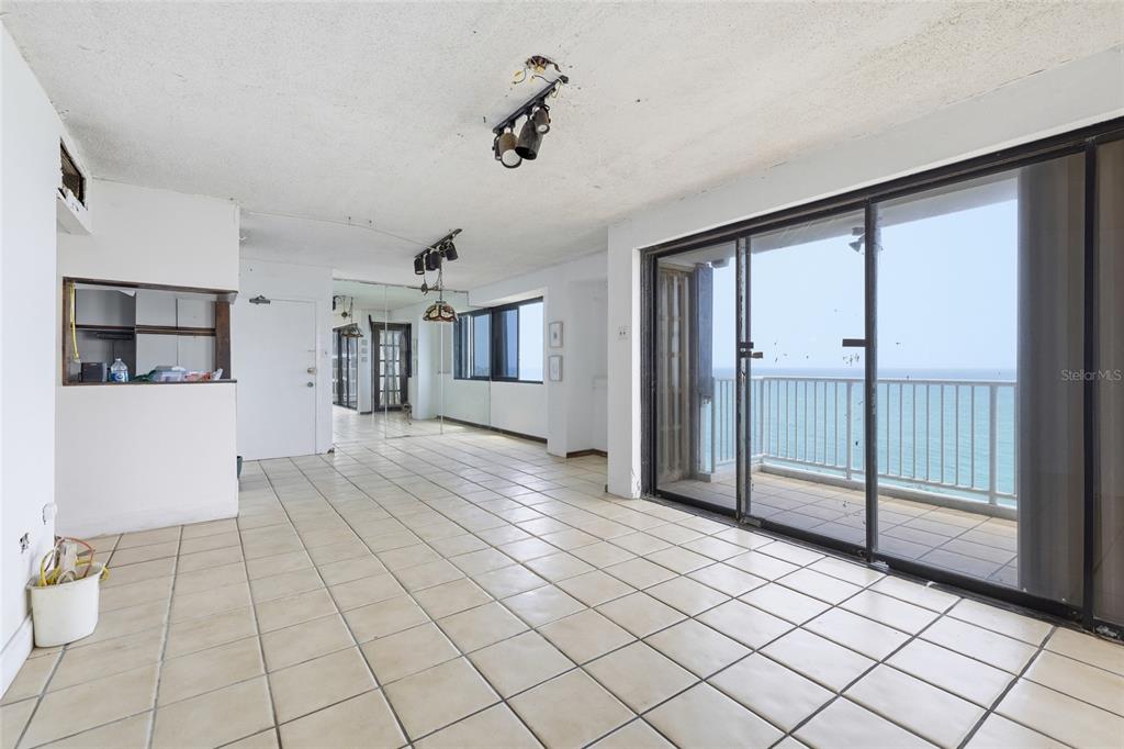 An empty room with tiled floors, track lighting, and a sliding glass door overlooking the ocean — 4633 ISLA VERDE AVE UNIT 803, CAROLINA, PR