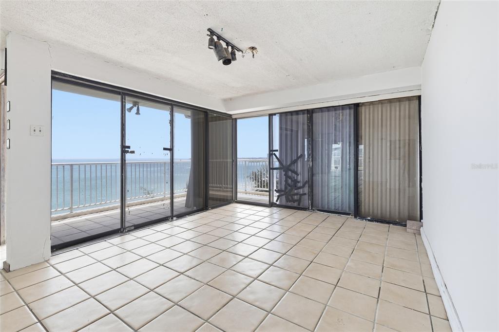 An empty room with beige tile flooring features floor-to-ceiling sliding glass doors overlooking the ocean — 4633 ISLA VERDE AVE UNIT 803, CAROLINA, PR