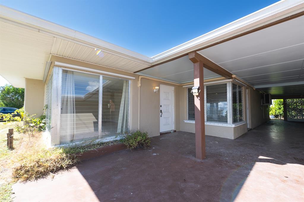 The exterior of a house features a concrete patio, a carport, and large windows — 410 W CHARLOTTE AVENUE, PUNTA GORDA, FL