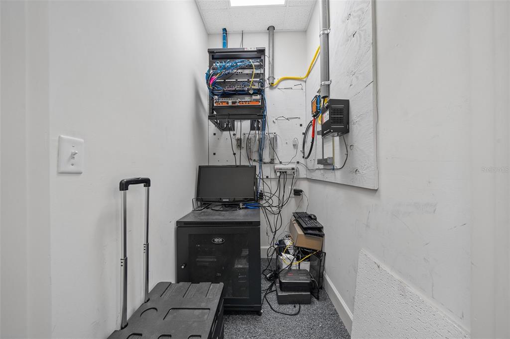 A small utility room contains a wall-mounted network rack, a server cabinet, and computer equipment — 5925 SE ABSHIER BOULEVARD, BELLEVIEW, FL