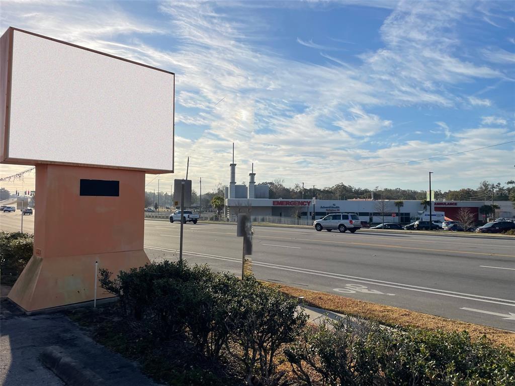 A large blank billboard stands beside a road near an AdventHealth emergency department building — 5925 SE ABSHIER BOULEVARD, BELLEVIEW, FL