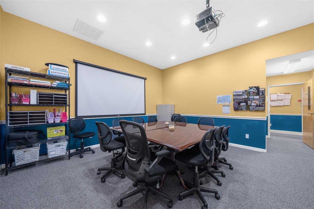 A conference room features a projector screen, a large table, and office chairs — 5925 SE ABSHIER BOULEVARD, BELLEVIEW, FL