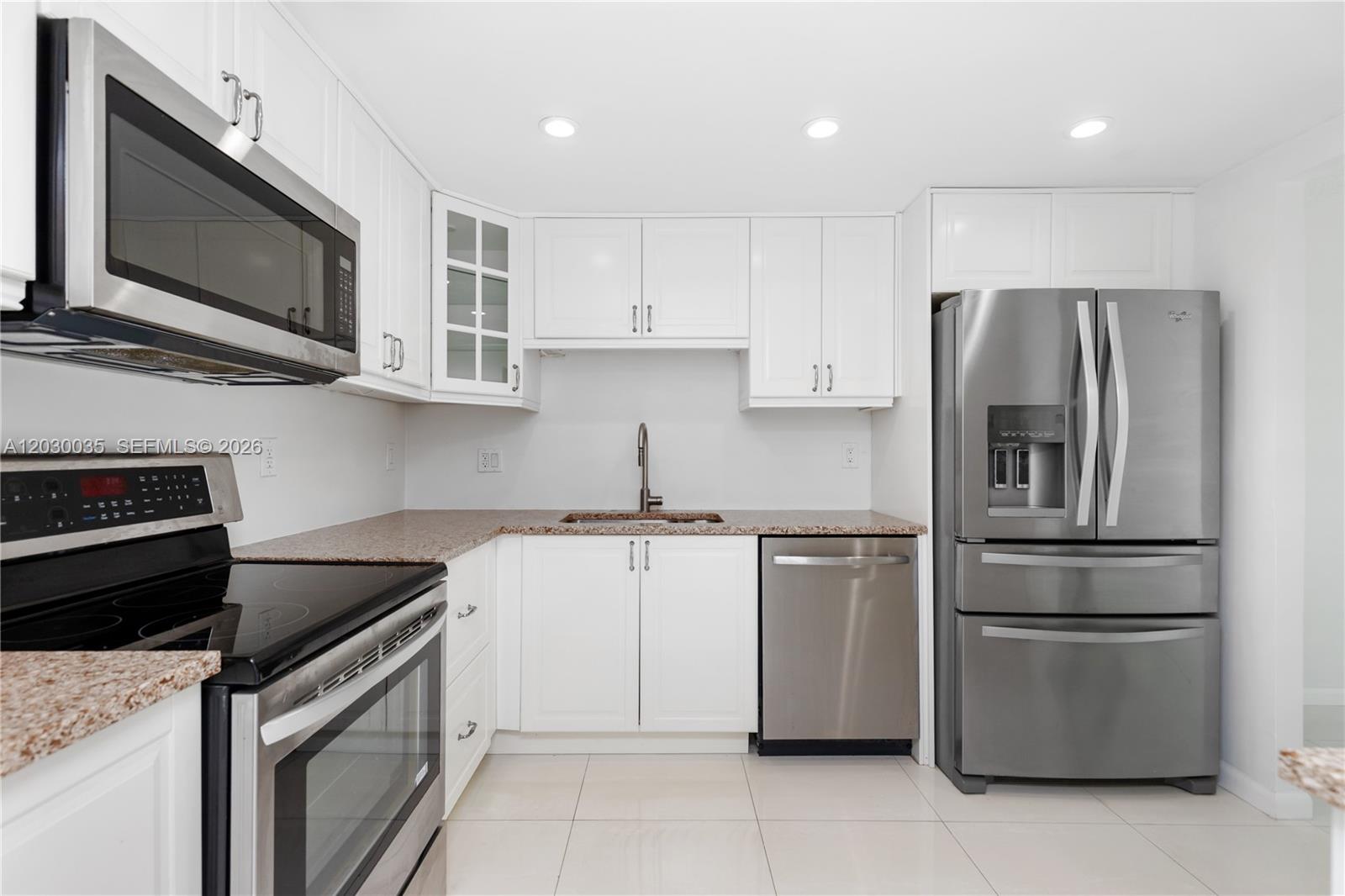 A kitchen features white cabinets, stainless steel appliances, and granite countertops — 210 Sea View Dr # 207, Key Biscayne FL 33149, KEY BISCAYNE, FL