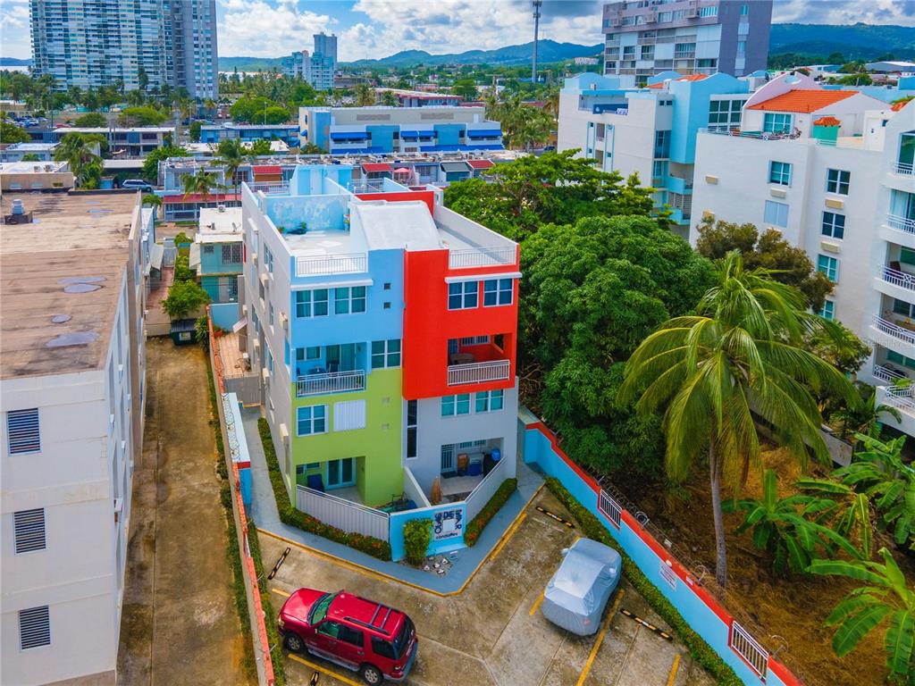 An aerial view shows a colorful multi-story apartment building with a parking lot in front — 707 OCEAN DRIVE UNIT A-4, LUQUILLO, PR