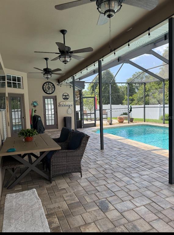 A bedroom features light wood-look flooring, a blue patterned quilt, and a sliding glass door — 12603 ROSELAND DRIVE, NEW PORT RICHEY, FL