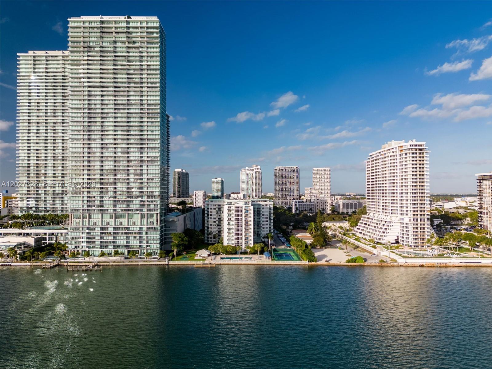 An aerial view shows several high-rise residential buildings situated along a waterfront with a pool — 3301 NE 5th Ave # 1015, Miami FL 33137, MIAMI, FL
