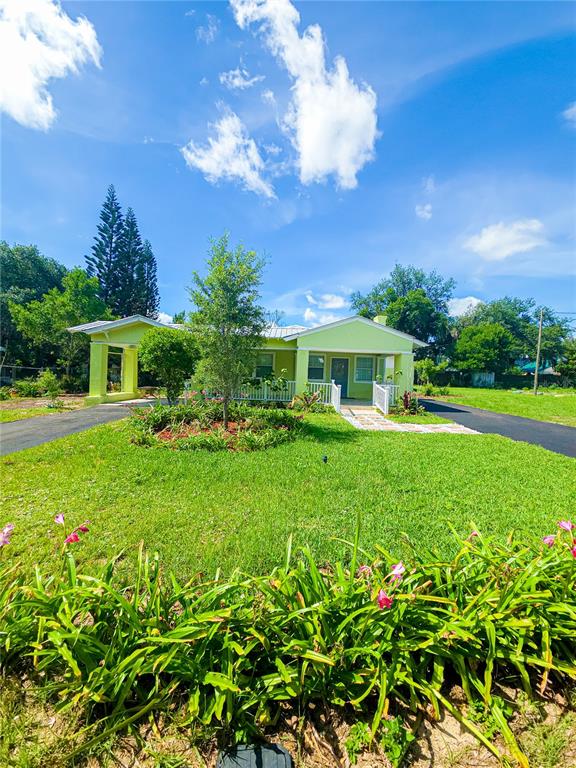 A light green single-story house with a carport and a front lawn under a blue sky — 17 WILKES STREET, AVON PARK, FL
