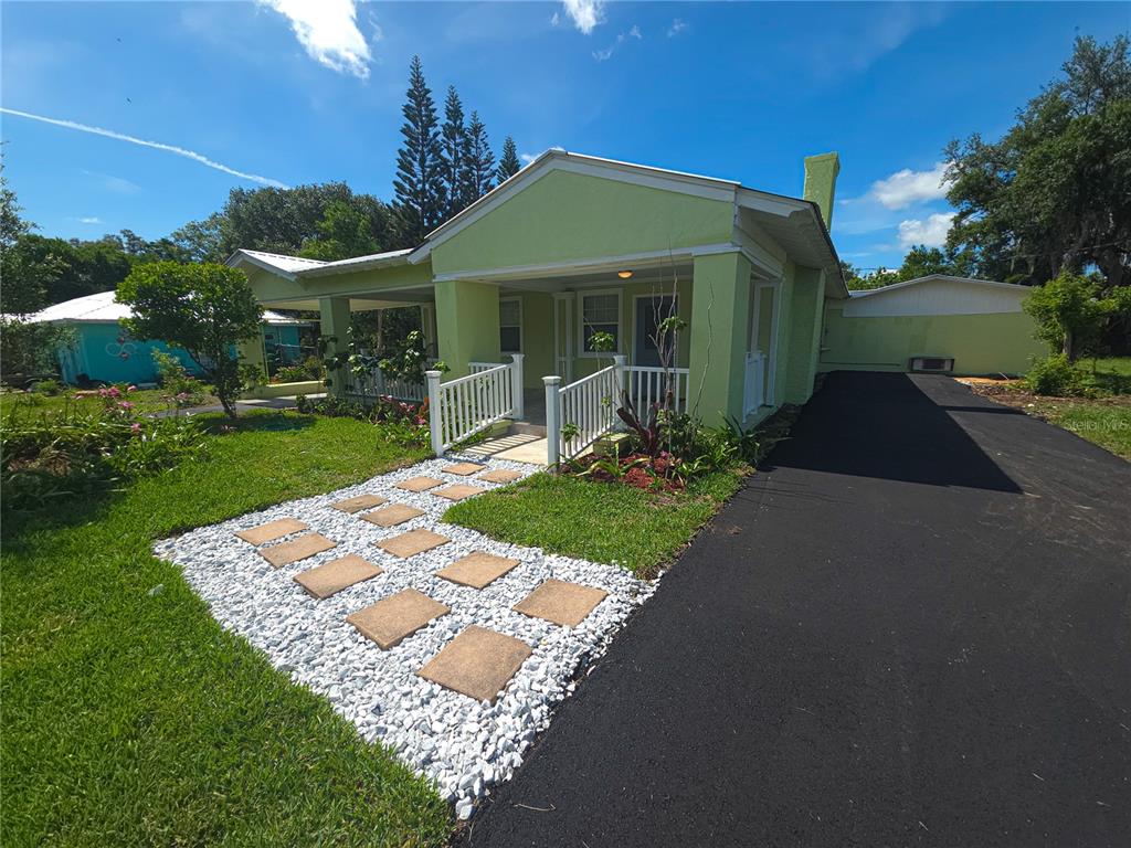A light green house with a covered porch, white railings, and a stone walkway — 17 WILKES STREET, AVON PARK, FL