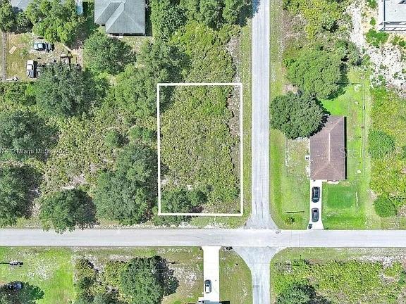 This aerial view shows a vacant, rectangular lot outlined in white next to a road — 2517 67TH STREET W, LEHIGH ACRES, FL