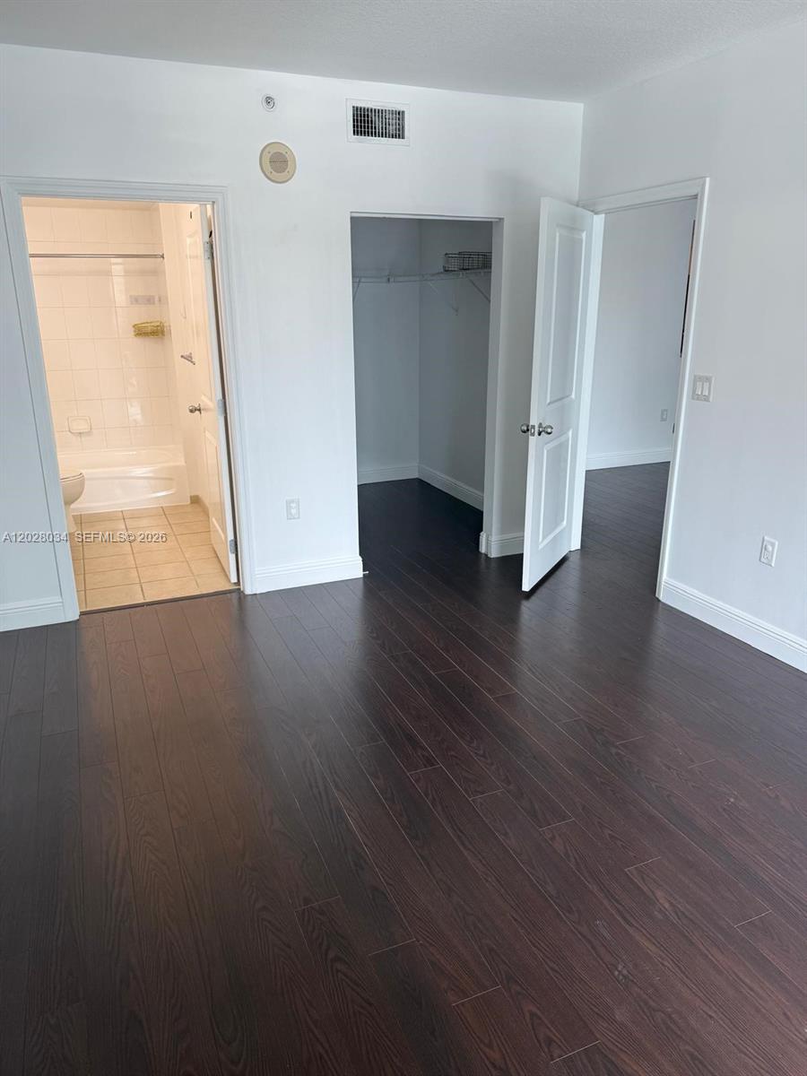 A room with dark wood flooring features a bathroom, a walk-in closet, and a doorway — 1250 S Miami Ave # 1412, Miami FL 33130, MIAMI, FL